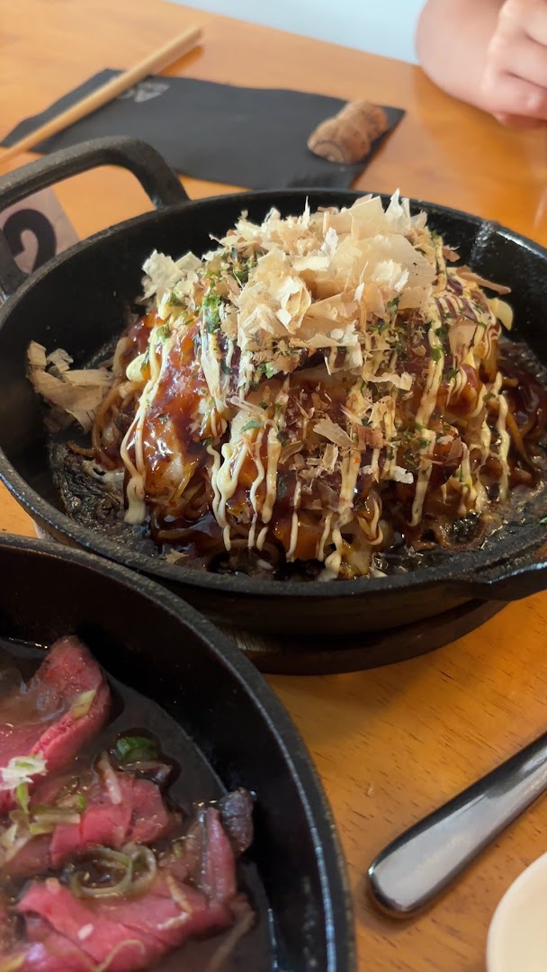 Okonomiyaki servi dans une poêle avec sauce et copeaux